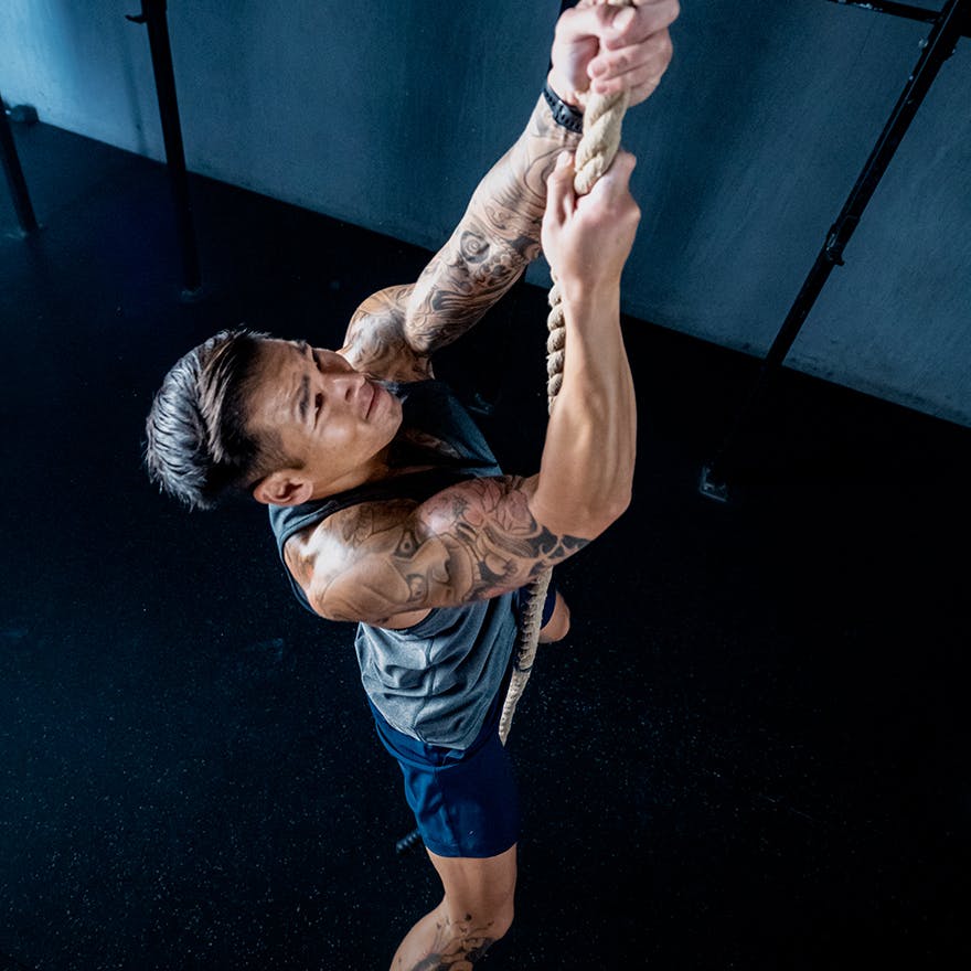 Don Tran climbing a rope in a gym.