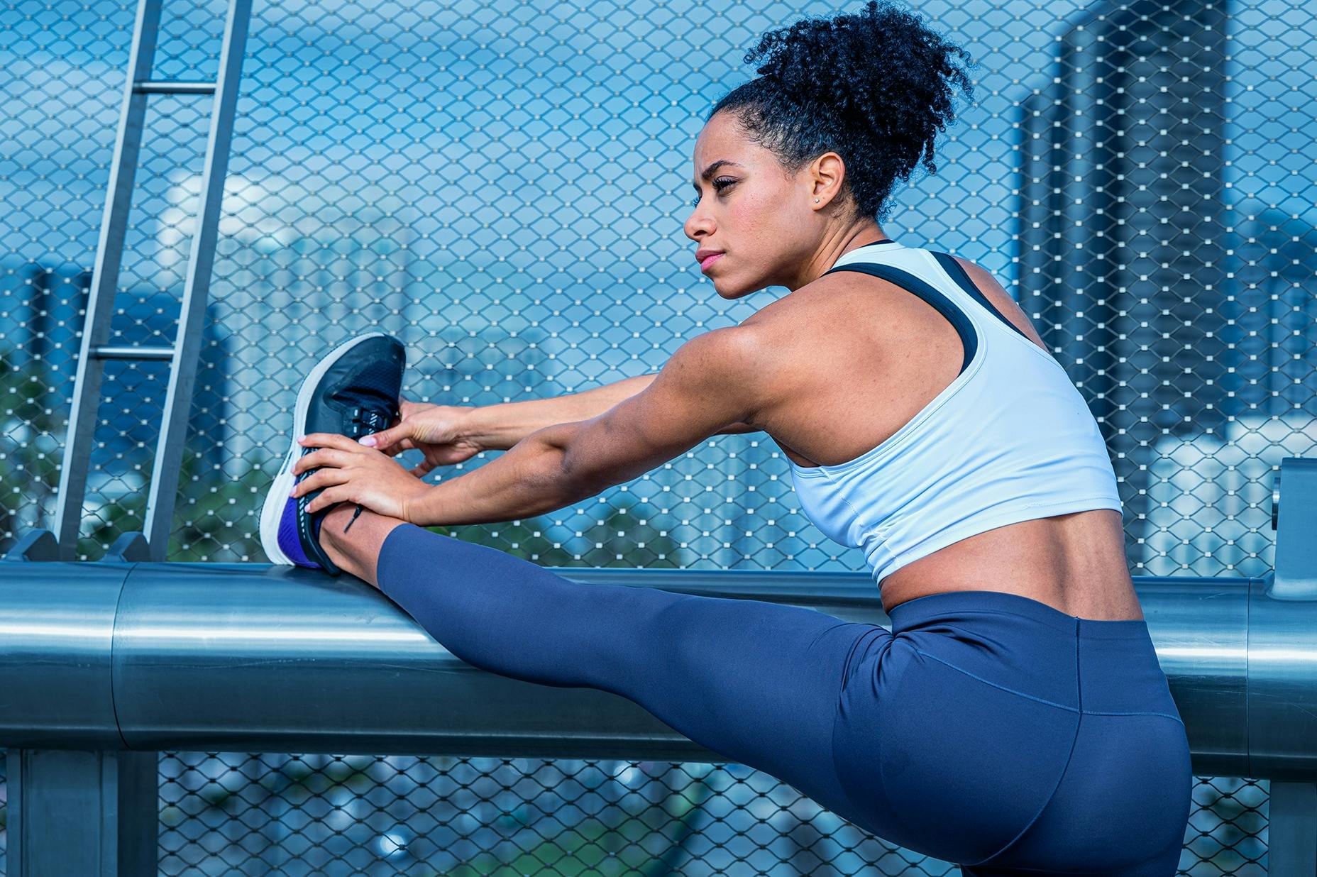 A woman in exercise clothes, stretching before going for a jog.