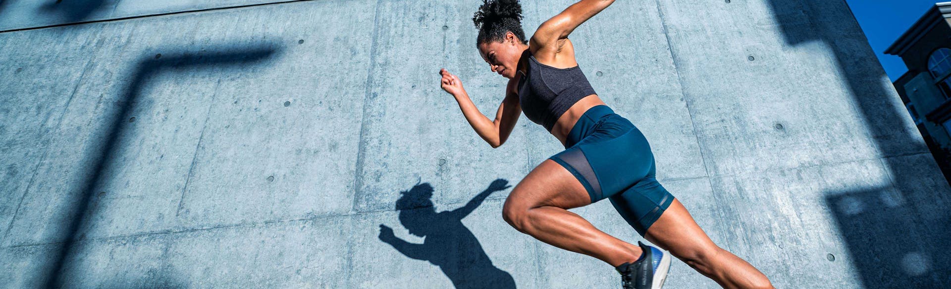 A woman jogging in front of a wall.