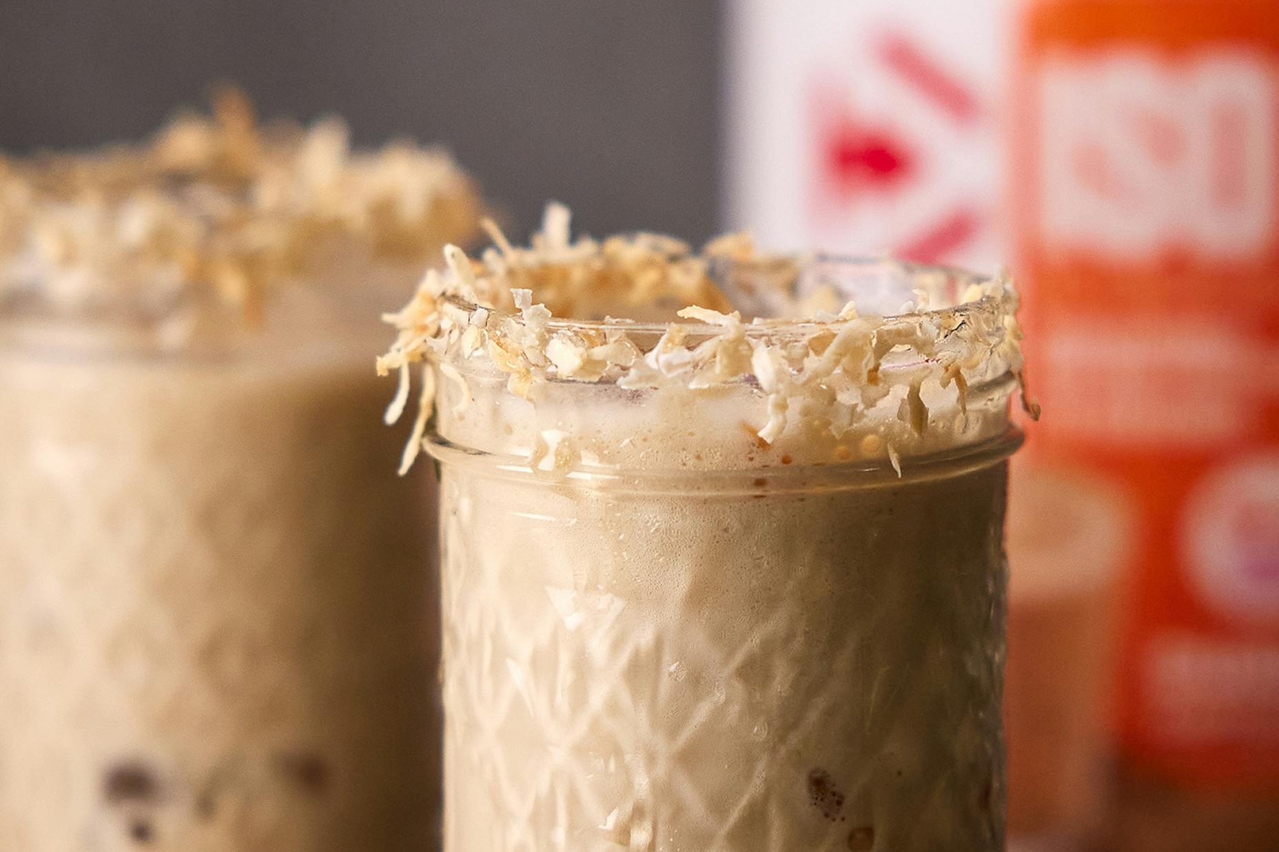 A glass mug filled with Iced Coconut Protein Cappuccino Flavored Drink.