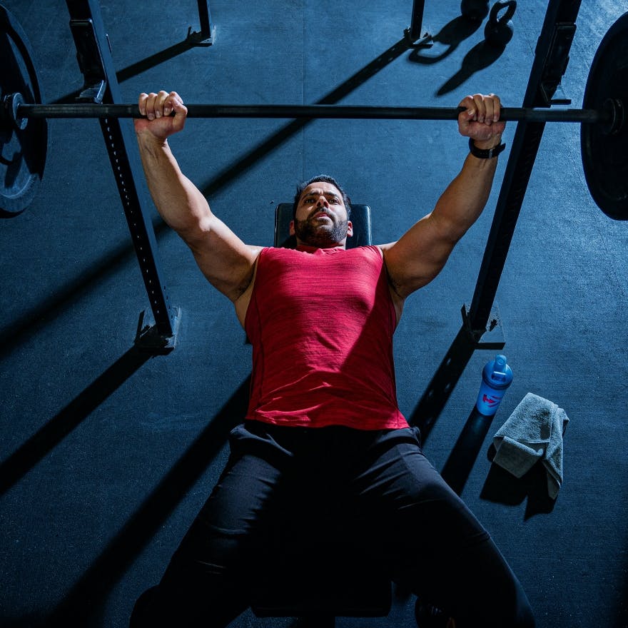 A man laying on his back on a weightlifting bench, lifting some weights.