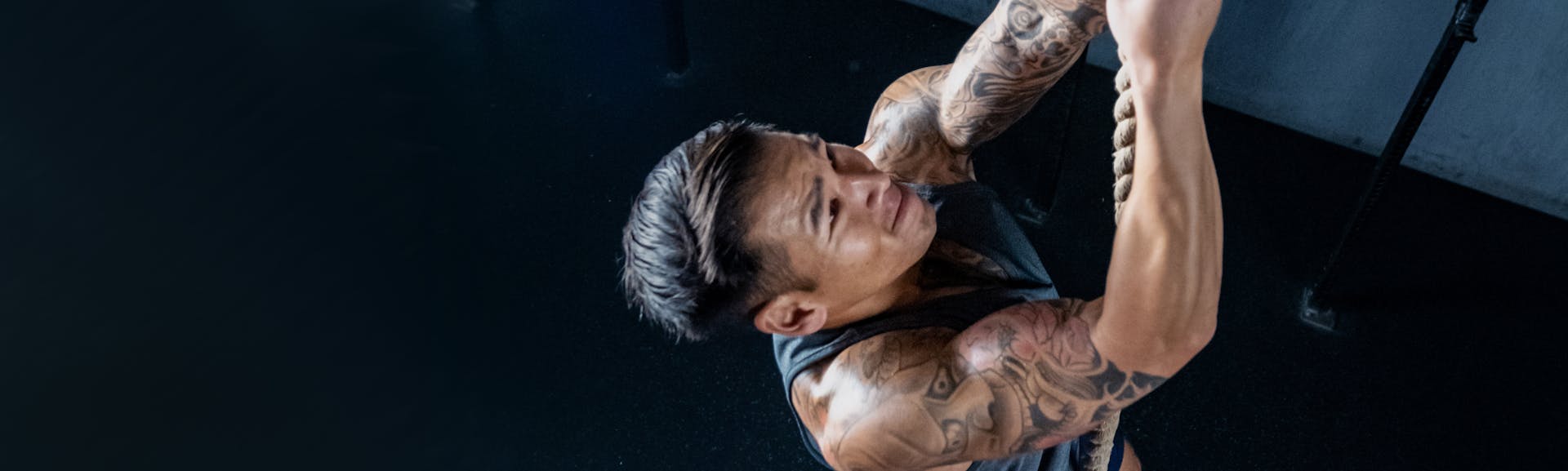 Don Tran climbing a rope in the gym