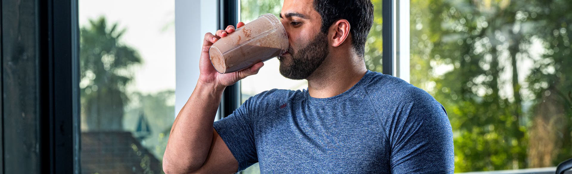 A man drinking a Dymatize Chocolate Protein Shake.